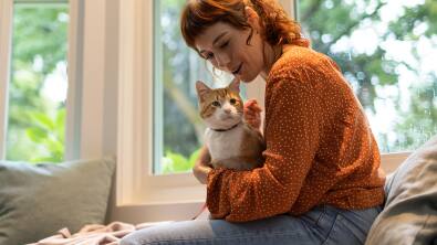 Mulher com uma sweatshirt laranja a segurar num gato
