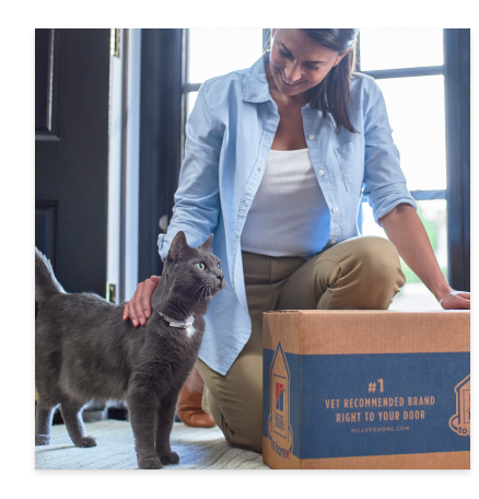 mulher com o seu gato preto e uma embalagem de alimento Hill's para gato